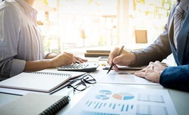 Two professionals reviewing financial charts and reports at a desk