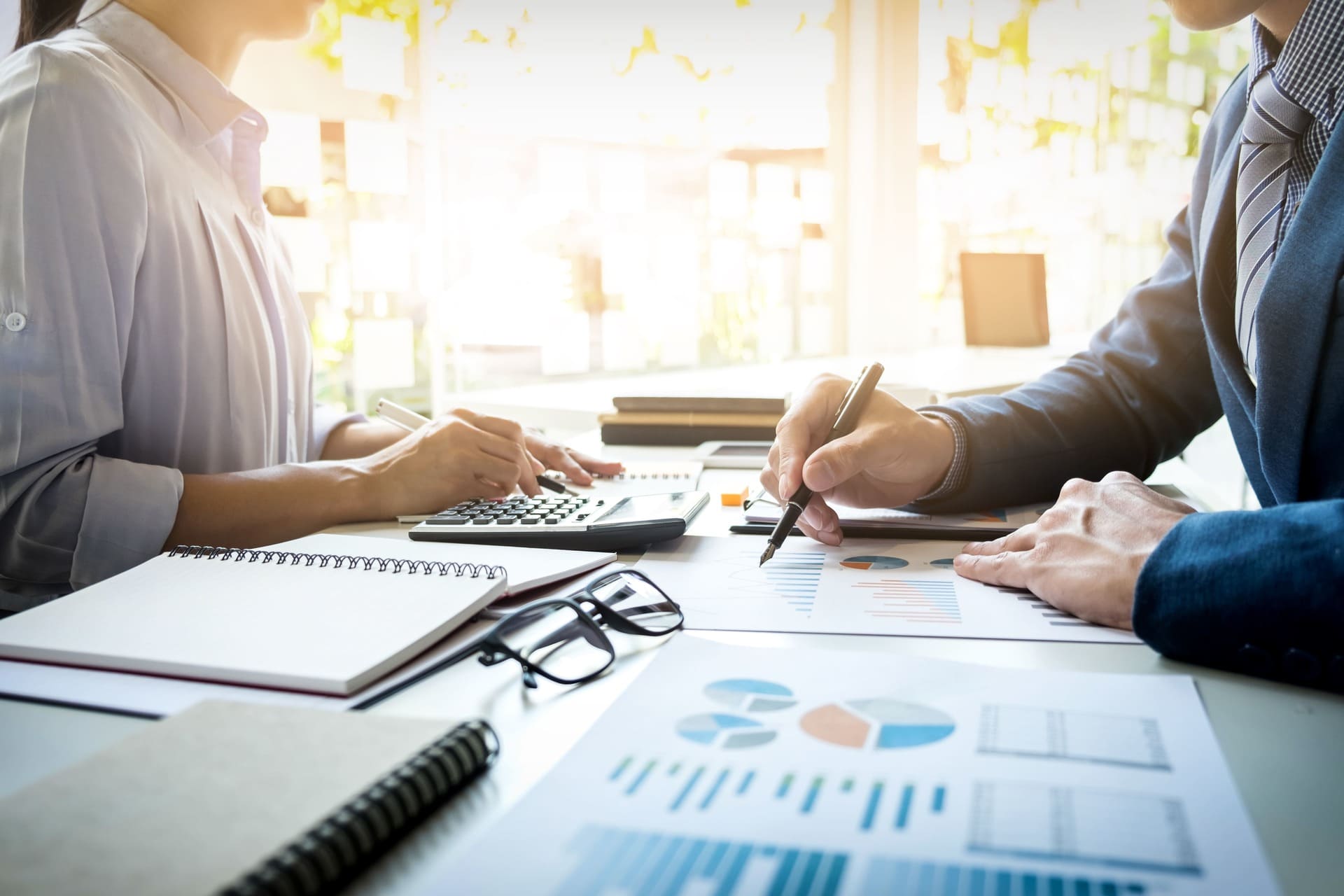 Two professionals reviewing financial charts and reports at a desk