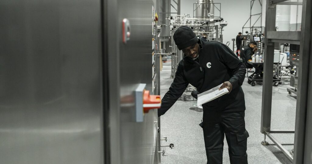 Auditor with a clipboard inspecting equipment inside a production facility