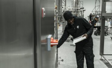 Auditor with a clipboard inspecting equipment inside a production facility