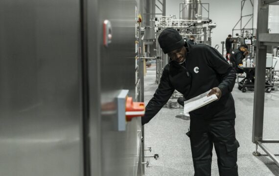 Auditor with a clipboard inspecting equipment inside a production facility