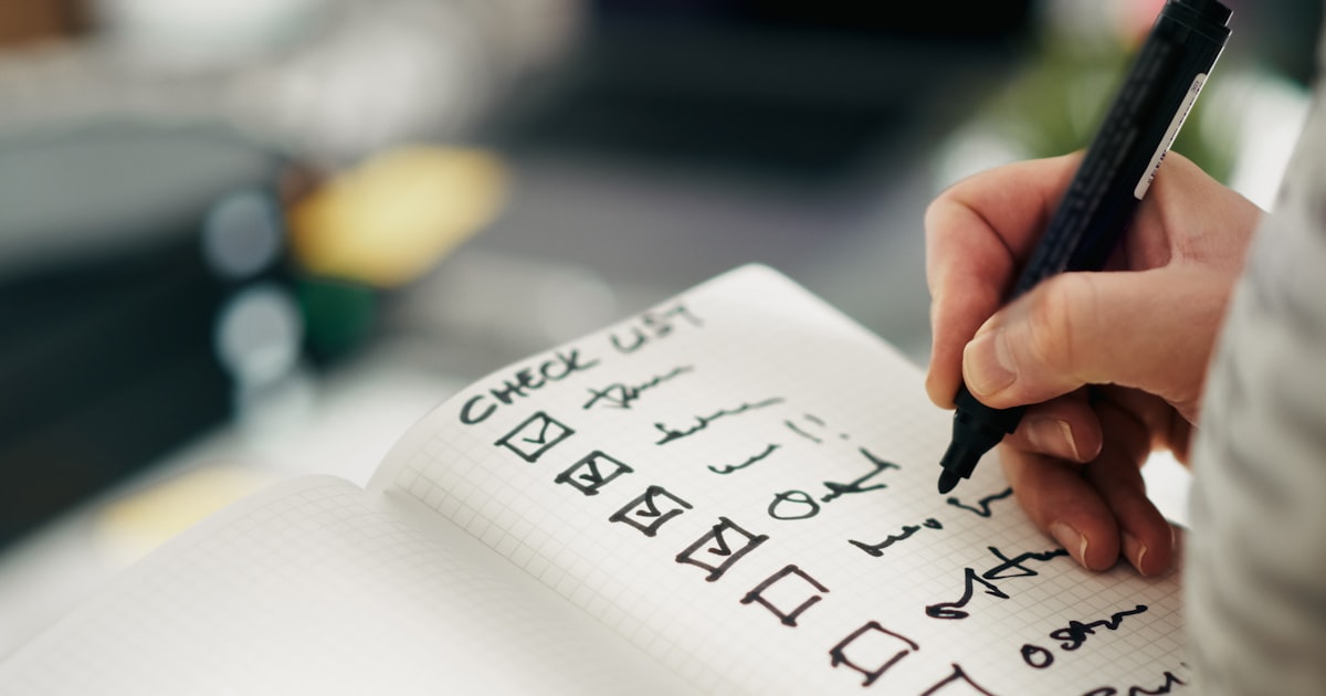 Hand ticking completed items off a handwritten checklist